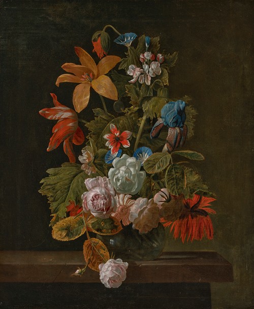 Tulips, roses, an iris and various flowers in a glass vase on a stone ledge