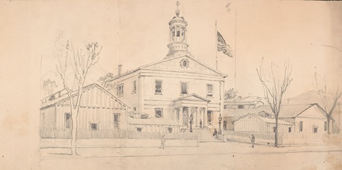 Courthouse or town hall surrounded by homes and outbuildings, American flag flying over roof at right